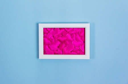 White frame with red hearts on blue background, copy space, valentine's day, love, invitation