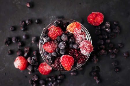 Close up of frozen mixed fruits and berries on a black table Healthy food vitamins snack dessertの写真素材