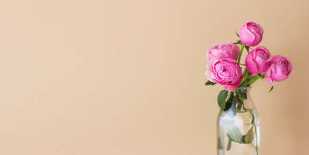 Spring flower arrangement of fresh roses in a vase on a beige pastel background. Festive floral concept with copy spaceの写真素材