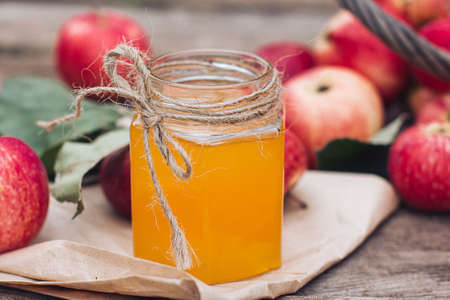 A jar of honey and red apples are lying on a wooden table. Autumn harvest, harvest season, autumn...