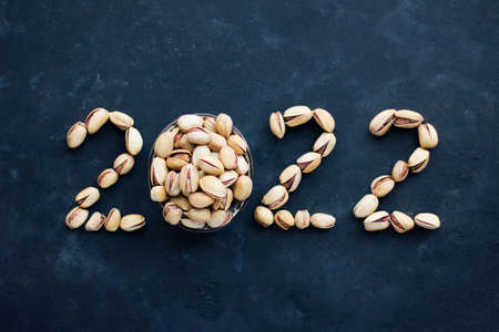 The numbers 2022 are made from eating pistachios, new year and Christmas, healthy food and a symbol...