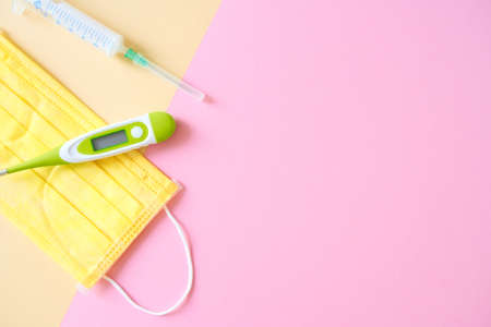 Pills, capsules, thermometer, surgical mask on the bright pink background
