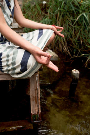 Beautiful young woman in dress meditating on the natureの写真素材