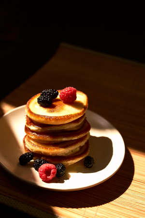 Pancakes with raspberry, mulberry and honey on the white plate. Top viewの写真素材
