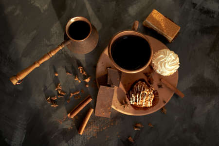Tasty desserts, cake, coffee and cinnamon on the dark background