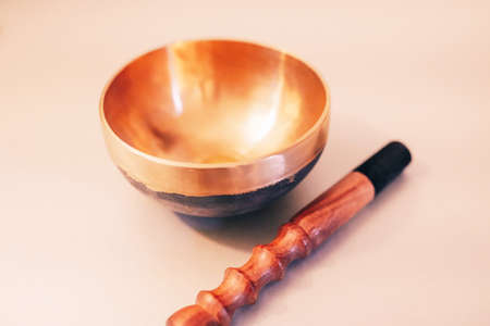 Bronze tibetan singing bowl with wooden stick on the white background. Sound healing, sound bath...