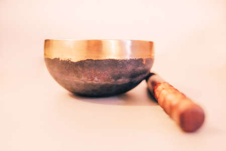 Bronze tibetan singing bowl with wooden stick on the white background. Sound healing, sound bath therapyの写真素材