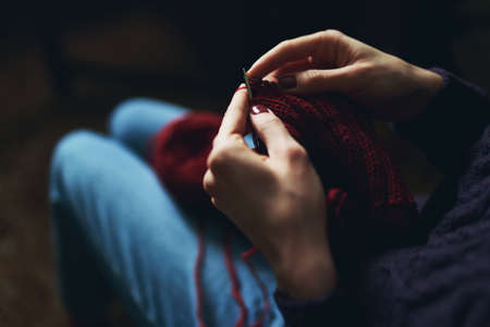 Female hands knitting with red yarn. Creative hobbyの写真素材