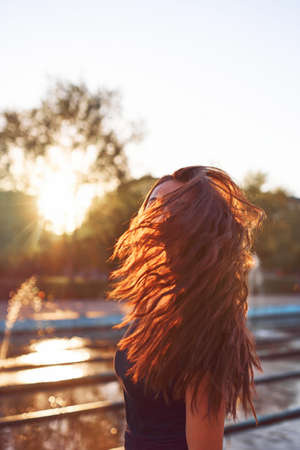 Beautiful young woman with flying hair at sunset timeの写真素材