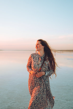 Portrait happy laughing woman in pink dress playful having fun on desert beach of salt pink lake. Ukrainian salt lakeの写真素材