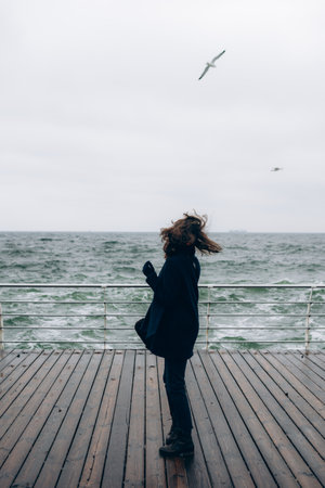 Portrait of a happy smiling woman walking outdoors in the sea shore beach on wind weather.の写真素材