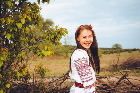 Photo of a smiling young woman in ethnic ukrainian shirt, enjoying the beautiful and peaceful weekend getawayの写真素材