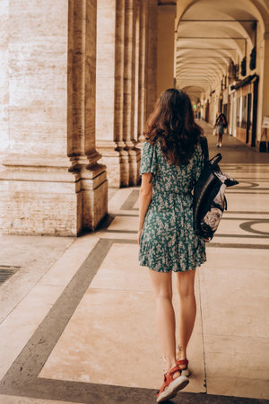 A beautiful woman walks with backpack in Turin, Italy. Beautiful historical architecture. Vacation in Italy, adventure lifestyleの写真素材
