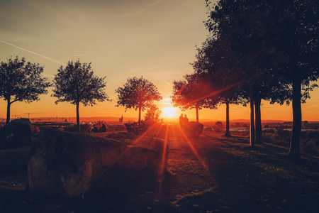 Silhouette of people and trees on the hill at the sunset timeの写真素材