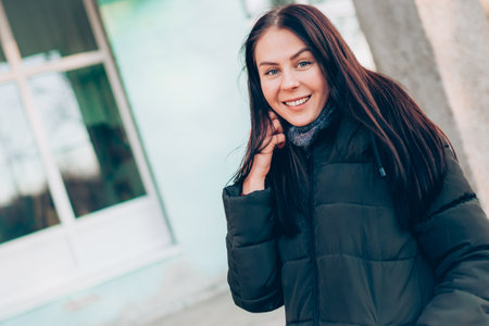 Portrait of young smiling brunette woman in winter jacket looking at camera.の写真素材