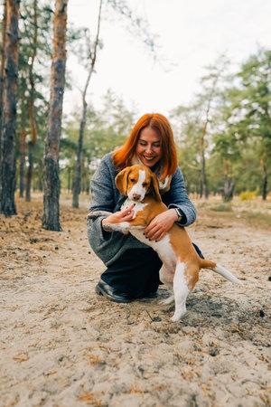 Happy woman with red hair embracing beagle dog in parkの写真素材