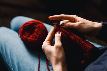 Cozy Knitting Session With Red Yarn: Hands Crafting A Warm Scarf For Relaxation And Home Comfort