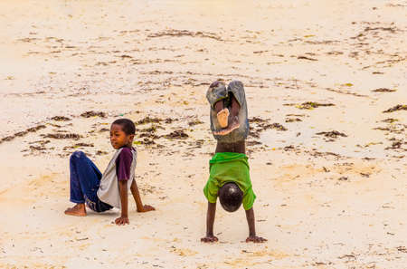 Zanzibar, Tanzania, March 21, 2018. Two small african children in in the sand in tattered  smutty...
