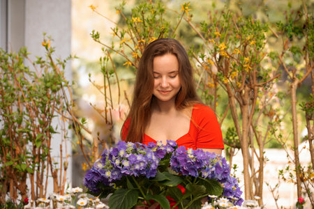 Beautiful young happy woman gardening outside in summer with many flowers. Garden, flowers and people conceptの写真素材