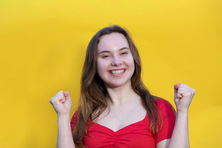 Closeup photo of pretty happy lady wearing red dress and looking empty space. isolated yellow color background. Young emotional girl concept. copy spaceの写真素材