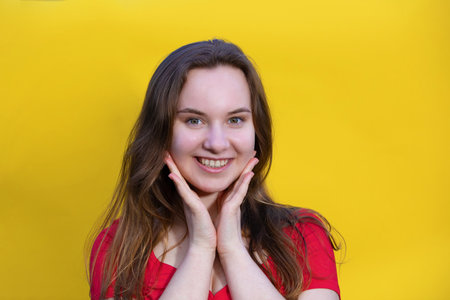 Closeup photo of pretty happy lady wearing red dress and looking empty space. isolated yellow color background. Young emotional girl concept. copy spaceの写真素材