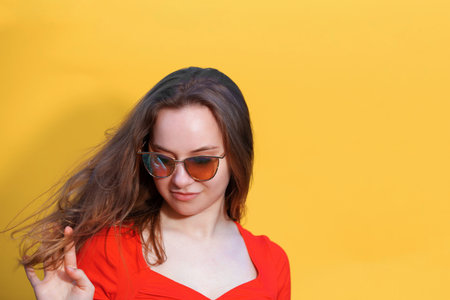 Closeup photo of pretty happy lady wearing red dress and looking empty space. isolated yellow color background. Young emotional girl concept. copy spaceの写真素材