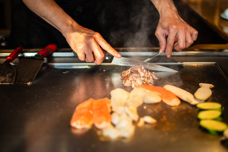 chef's hands with spatula over teppanyaki. cooking vegetables meat and seafood on hot hibachi grill table. Traditional Japanese Cuisine. Teppan showの写真素材