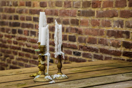 vintage candlesticks with candles on brick wall backgroundの写真素材