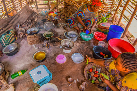 Stone Town, Zanzibar, Tanzania. 27 March 2018. two African women cooking food on a fire in a hut of branchesの写真素材