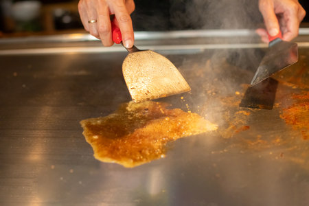 chef's hands with spatula over teppanyaki. cooking vegetables meat and seafood on hot hibachi grill table. Traditional Japanese Cuisine. Teppan showの写真素材