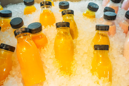 Healthy fresh juice freeze in ice. several plastic bottles of juice stand cooling in ice, ready for...