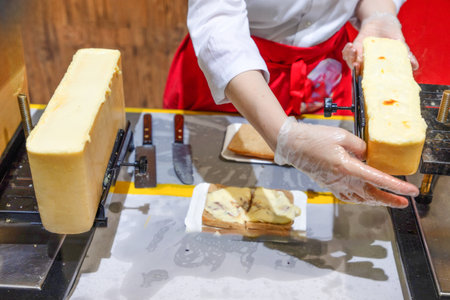 wheel of raclette cheese has been heated on raclette machine. molten state when served to customers waiting for this tasty European delicacy. Traditional French foodの写真素材