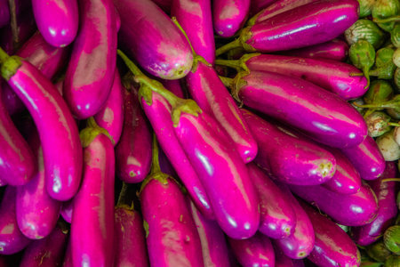 large pile of long thin pink asian eggplants background displayed for sale in a market in sri lankaの写真素材