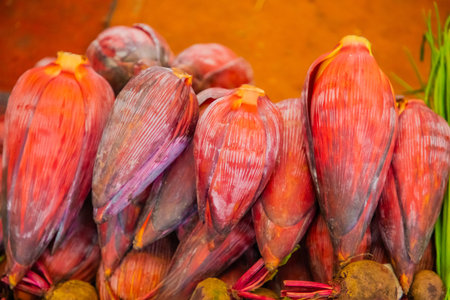 A bunch of large red buds of banana palm flowers lie on a market counter in Sri Lanka, fresh and ready for sale. Asian cuisine and ingredient natural backgroundの写真素材
