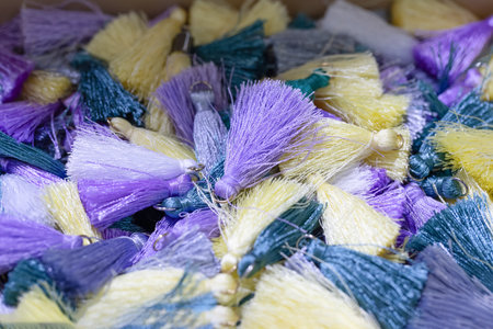 Vibrant collection of colorful tassels in shades of purple, yellow, and green, showing intricate...
