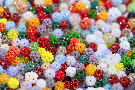 A vibrant collection of beads in assorted colors and shapes, showing intricate details and textures,...