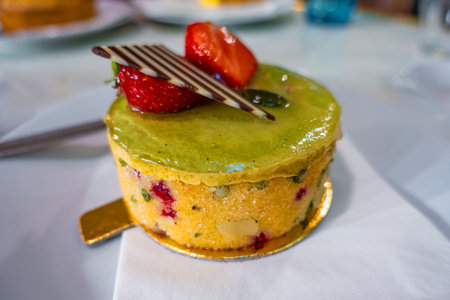Delicious round cake topped with fresh strawberries and chocolate, served on a white napkin in a...
