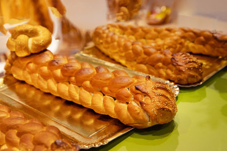 Braided bread loaves are beautifully arranged on a silver tray, showcasing golden crusts against a...