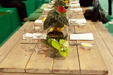 Beautifully set dining table featuring fresh flowers, glassware, and napkins, creating an inviting...