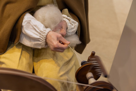 Female artisan is skillfully spinning wool using a traditional spinning wheel, showcasing...