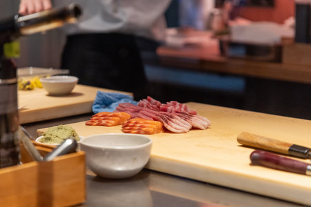 Assorted sushi ingredients are beautifully arranged on a wooden cutting board, showing vibrant...
