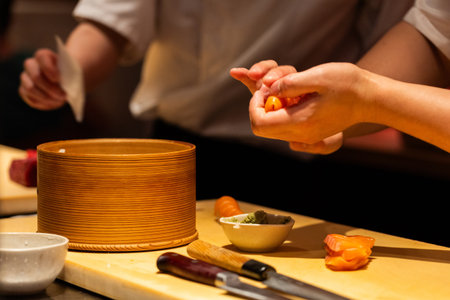 Skilled chef is preparing sushi with fresh ingredients, showcasing vibrant colors and textures, in a professional kitchen environment.の写真素材