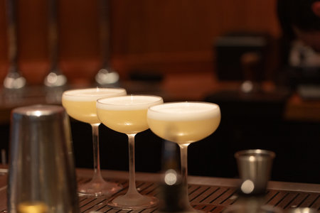 Elegant cocktails are beautifully arranged in stylish glasses on a polished bar counter, showcasing...