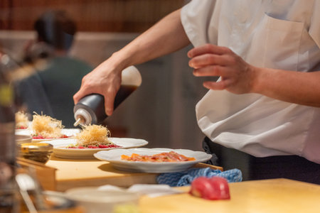 Chef is skillfully plating gourmet dishes with attention to detail in a contemporary kitchen, showcasing culinary artistry and creativity.の写真素材