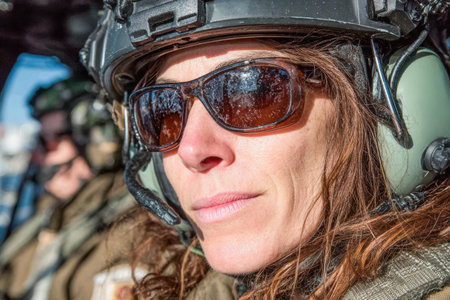 Female pilot is wearing a helmet and sunglasses inside an aircraft cockpit, showing determination and readiness for flight.の素材