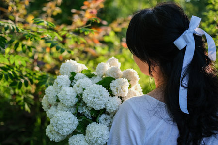 Romantic portrait of a young woman with a bouquet of white flowers in a summer garden. summer...