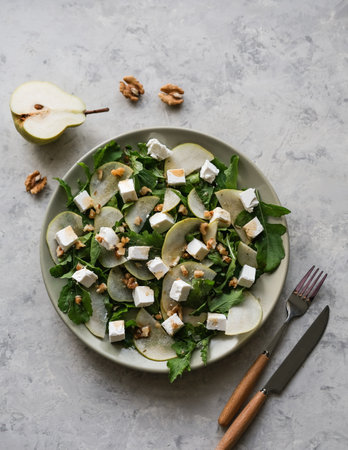 Salad with arugula, pear, feta cheese and walnuts. Delicacy salad on a plate on a gray backgroundの写真素材