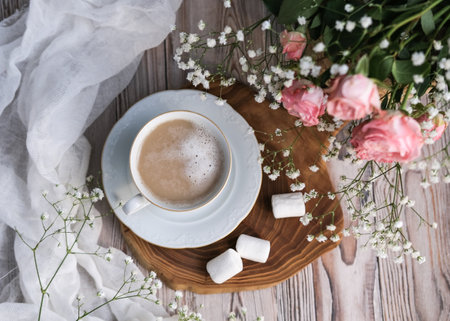 Top view of a cup of coffee and a bouquet of flowers on a wooden table.の写真素材
