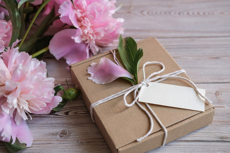 Mock up tag, kraft gift boxes decorated with flowers peonies. Preparation of gifts for mother's day, birthday, women's holiday. Gift wrapping ideaの写真素材