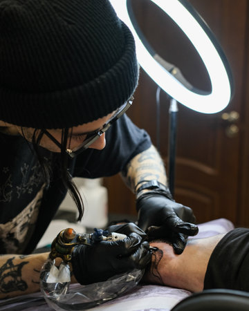 Professional tattoo artist stuffs a tattoo on the man's hand. Tattoo artist at work. Tattoo creation process. Art and creativityの写真素材